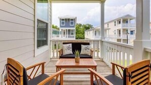 A covered outdoor seating area with wooden furniture and a view of adjacent buildings. - Pass Christian Vacation Rental < 1/2 Mi to Beach! (Pass Christian)