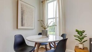 A dining area with a round table, four black chairs, a potted plant, and a framed artwork on the wall. - Pass Christian Vacation Rental < 1/2 Mi to Beach! (Pass Christian)