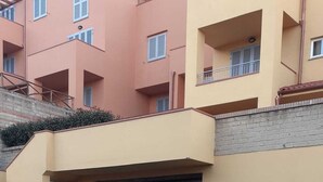 A multi-story building with a parking area in front. - Sea view apartment (Castiglione della Pescaia)