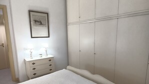 A bedroom with a large bed, a dresser, and a wardrobe. - Sea view apartment (Castiglione della Pescaia)