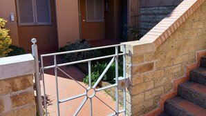 A building with two doors, a staircase, and a gated entrance. - Sea view apartment (Castiglione della Pescaia)