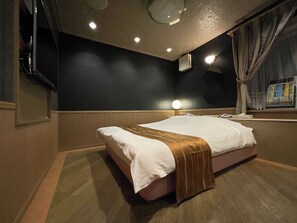 A hotel room with a bed, a nightstand, a lamp, a mirror, and a window with curtains. - HOTEL LAKEINN (Ono)