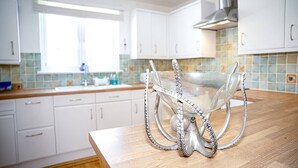 A modern kitchen with white cabinets, a wooden countertop, and a unique octopus-shaped serving dish.