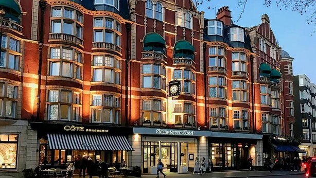Un hotel de varios pisos con un estilo arquitectónico clásico, con ventanas amplias y un reloj destacado.
