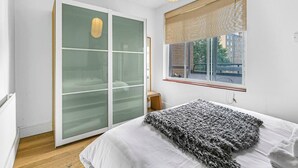 Un dormitorio con cama, puerta corrediza de vidrio, ventana con vistas y una lámpara colgante.