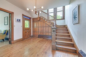 Une pièce spacieuse dotée d’un plancher en bois, d’un escalier avec une rampe en bois et d’une grande fenêtre qui laisse entrer la lumière naturelle.