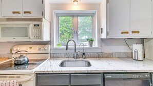 A kitchen with a built-in microwave, stove, sink, and dishwasher. There is a window with a view of trees outside. - Family Home w/ Yard & Fire Pit in Middleburgh! (Middleburgh)