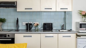 Une cuisine compacte avec des meubles de couleur claire, un four à micro-ondes, un grille-pain et une machine à café posés sur le plan de travail.