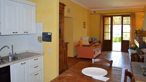 Una cocina compacta con armarios blancos, un lavamanos y un comedor con mesa y sillas.