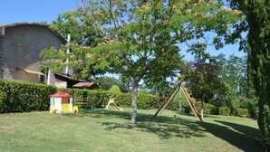 Un parque infantil con un columpio, una casita de juegos y un árbol con flores rosadas.