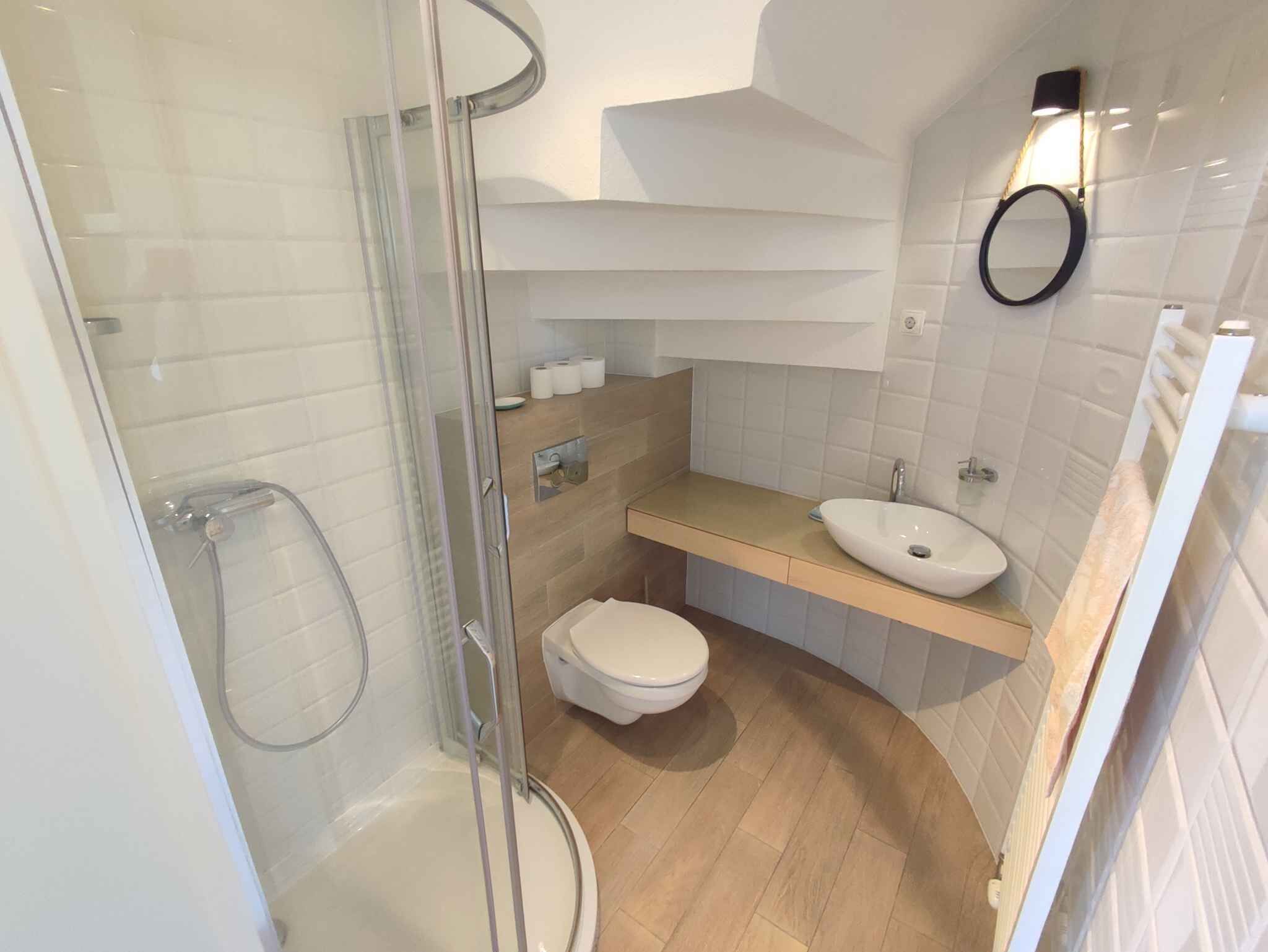Un bagno moderno con box doccia in vetro, un water bianco, un lavandino con specchio e un porta asciugamani.