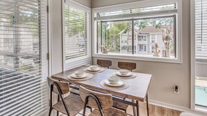 A dining area with a table set for four, four chairs, and a large window with blinds. - 1 Block to Beach: Myrtle Beach Condo w/ Pool! (Myrtle Beach)