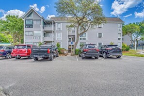 A parking lot with several SUVs and a multi-story building with balconies in the background. - 1 Block to Beach: Myrtle Beach Condo w/ Pool! (Myrtle Beach)