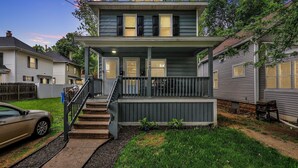 A two-story house with a front porch, a staircase, and a garage. - Charming 1 Bedroom House in Lansing, MI (Lansing)