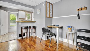 A modern kitchen with white cabinets, a wooden countertop, and a black chair. There is a small table with a water bottle and a bag of chips. - Charming 1 Bedroom House in Lansing, MI (Lansing)