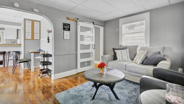 A modern living room with a grey sofa, a round coffee table, and a wooden floor. - Charming 1 Bedroom House in Lansing, MI (Lansing)