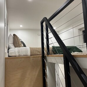 Cozy retreat with a low platform bed and staircase to an upper level.