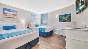A hotel room with two beds, a TV, and artwork on the walls. - Pelican Pointe 323:Walk to Beach~Pool~Free Parking (Clearwater Beach)