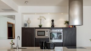 A modern kitchen with a central island, built-in appliances, and a large window. - Luxury 2 Bedrooms Flat Next to Harrods (London)