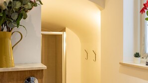 A bathroom with a shower, a sink with a yellow vase of flowers, and a window with a plant. - Luxury 2 Bedrooms Flat Next to Harrods (London)