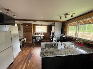 A compact kitchen with a built-in oven, a sink, and a window with a view of the outdoors.