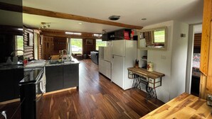 A spacious kitchen with wooden floors, a central island, and a dining area with a wooden table.