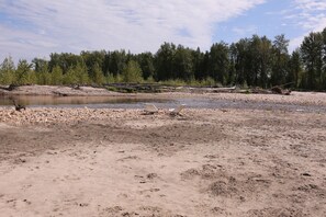 A riverbank with pebbles and a wooden chair.