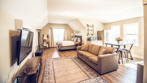 A spacious loft apartment with a large living area, a dining table, a kitchenette, and a bedroom. - Red Dog Farms Modern Studio Apt (Rocky Point)