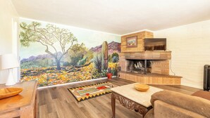 A living room with a mural, a fireplace, and a TV. - The heart of the desert with amazing views and hiking trails right outside! (Tucson)
