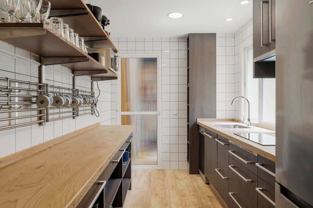 Een moderne keuken met houten aanrechtbladen, roestvrijstalen apparatuur en een ingebouwde oven.