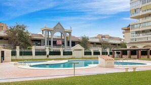 A hotel courtyard with a swimming pool, a covered pavilion, and a sign for 'SUPER COR'.