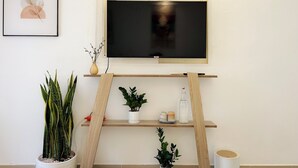 A modern living room with a mounted TV, wooden shelves, and various potted plants. - TRIP HOME stay & studio (Ho Chi Minh City)