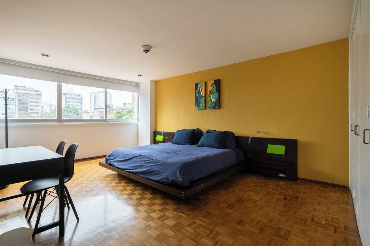 A modern bedroom with a large bed, a dining table, and chairs.