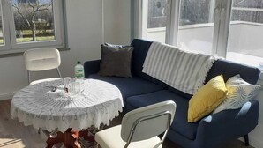 A cozy living area with a blue sofa, a white chair, and a round table with a lace tablecloth.
