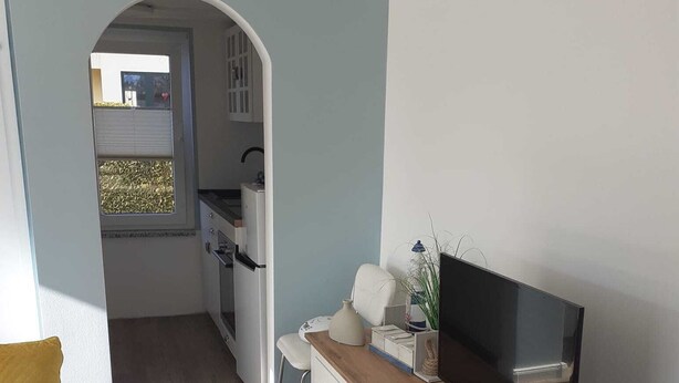 A compact living space with a kitchenette, a television, and a small dining area.