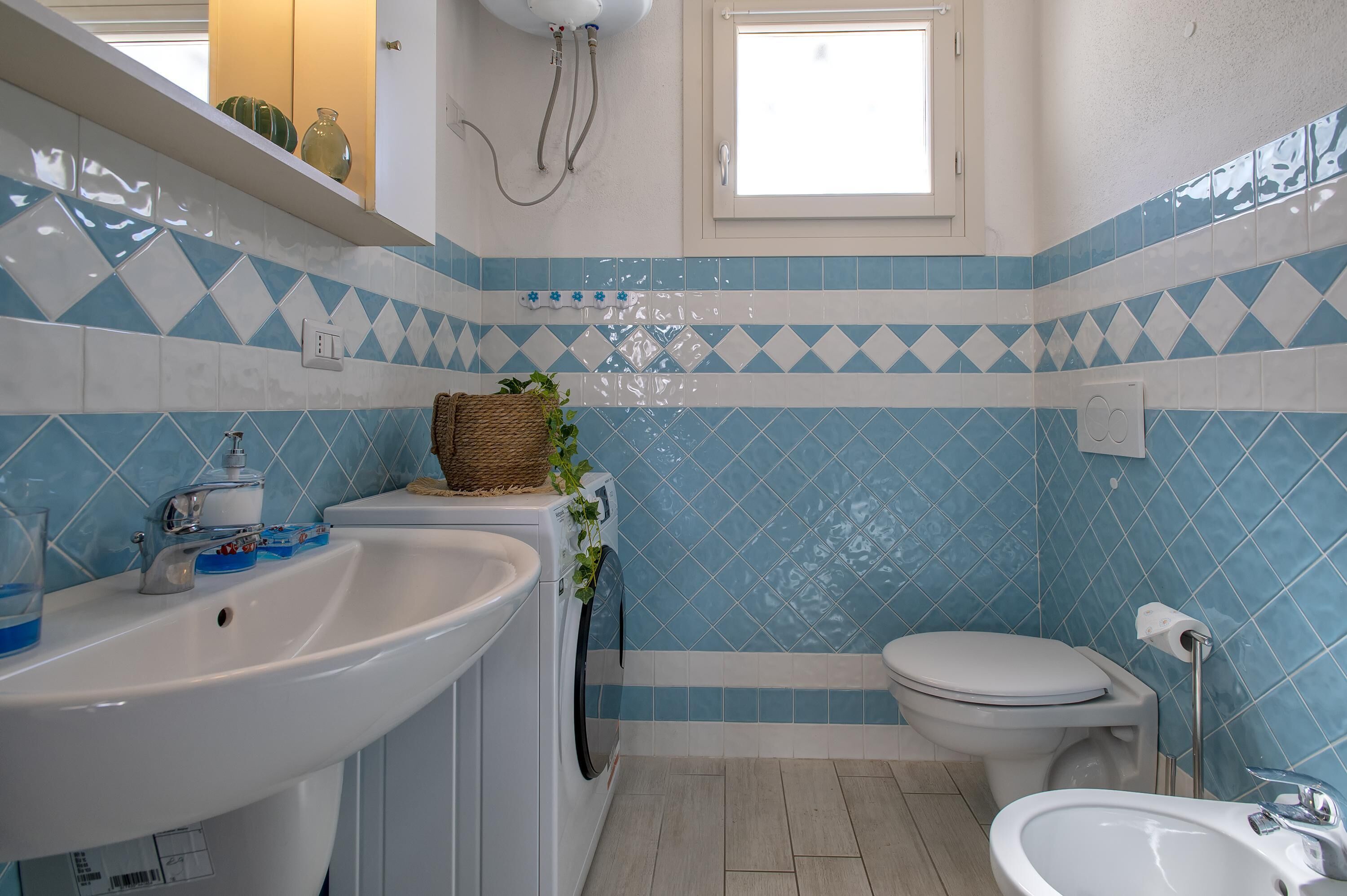 A bathroom with a sink, toilet, and a washing machine.