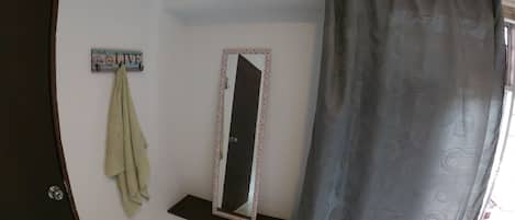 A bathroom with a shower curtain, a towel hanging on a rack, a mirror with a decorative frame, and a sign on the wall.