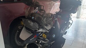 En motorcykel parkerad i ett garage med ett tak av trä och ett klinkergolv.