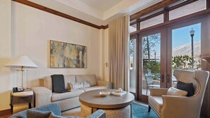 A well-lit living room with a sofa, armchair, and round coffee table. A painting hangs on the wall, and a lamp is on a side table. - The Aspen Mountain Residences 02AB - 2 Bedroom Residences (Aspen)