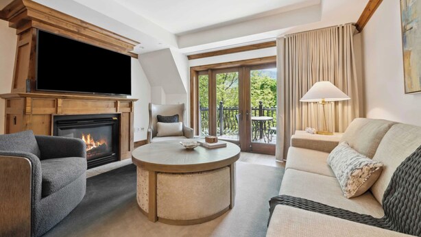 A cozy living room with a fireplace, a flat-screen TV, a round coffee table, and a sofa.