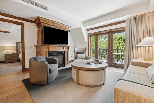 Ein großzügiges Wohnzimmer mit Kamin, Fernseher und einem Balkon mit Gartenmöbeln.