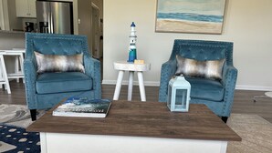 A living room with two upholstered chairs, a coffee table, a small side table, and a decorative lantern. - Large, beautiful house! 1.5 miles to Bethany Beach! Resort style amenities!!! (Ocean View)
