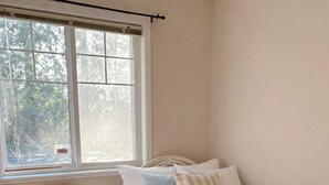 A bedroom with a bed, two chairs, a window, and a radiator. - Coquitlam Centre Mall 3 Bed 1 Bath in a Shared House (Port Coquitlam)