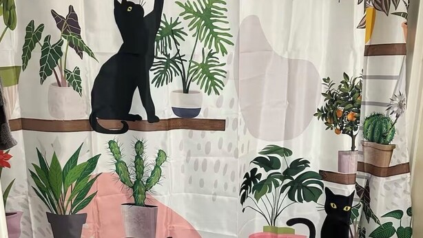Eine Duschvorhang mit einem Design aus Pflanzen und Katze.