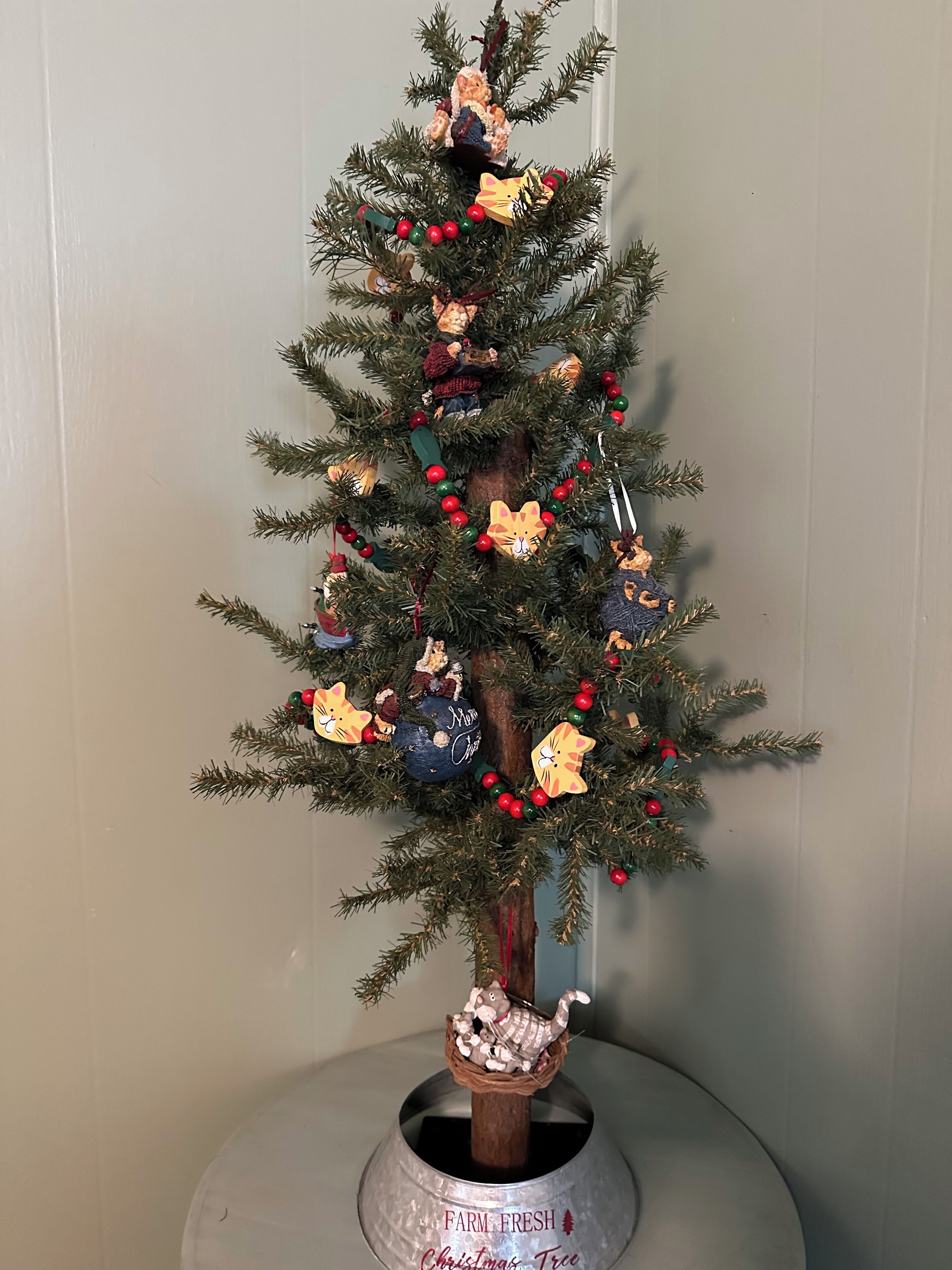 Een kerstboom met versieringen, een ster en een kerststal op een standaard.