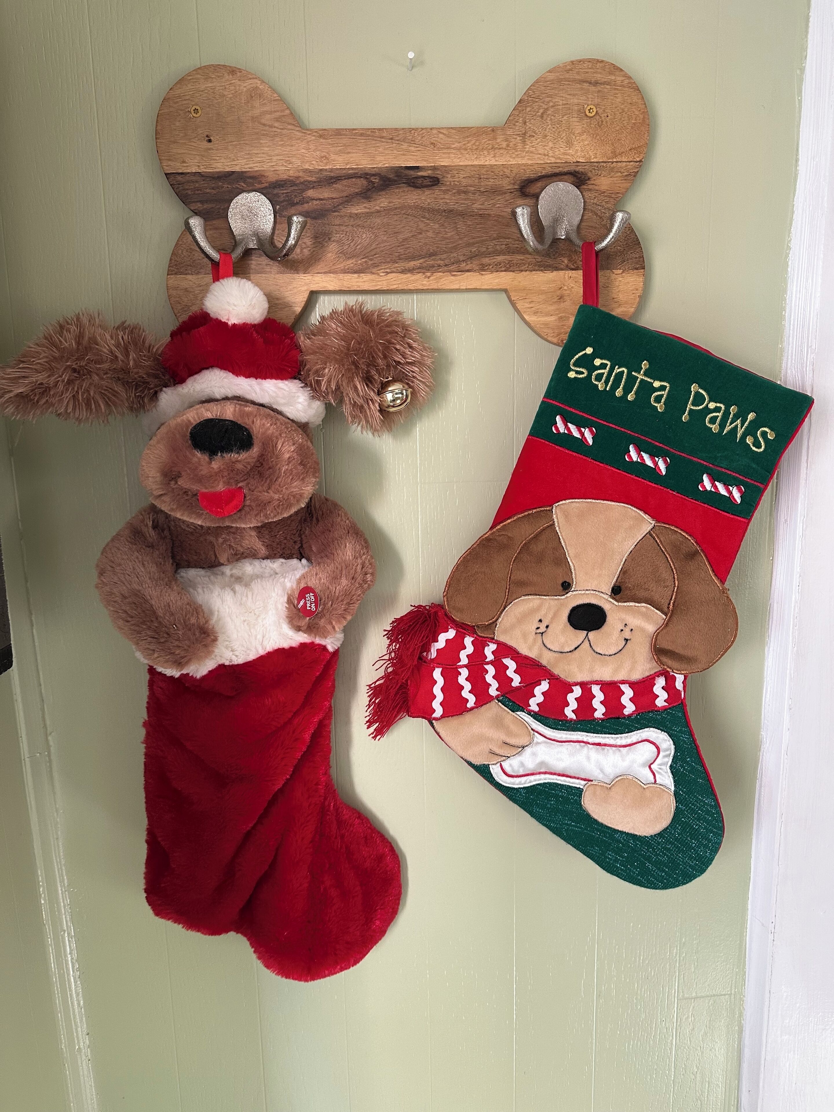 Eine an der Wand befestigte Holzablage mit zwei weihnachtlichen Dekorationen: ein plüschiges Rentier und eine Weihnachtsmütze für den Vierbeiner.