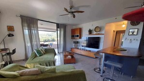 A modern living room with a sofa, TV, and bar area. - TAHITI OCEAN VIEW HOME (Papeete)