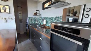 A modern kitchen with a built-in oven, microwave, and a stainless steel range hood. - TAHITI OCEAN VIEW HOME (Papeete)
