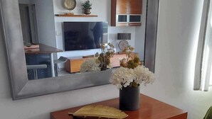 A modern kitchen with a wooden cabinet, a vase with flowers, and a large mirror reflecting the room. - TAHITI OCEAN VIEW HOME (Papeete)