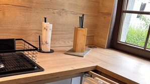 Una cocina con refrigerador empotrado, encimera de madera y ventana con vista a follaje.